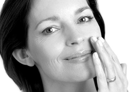 Middle-aged woman touching left cheek with hand.